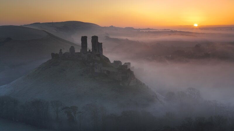 Castle ruins at sunrise in fog