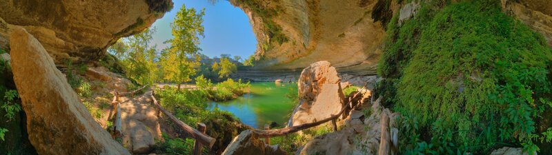 cave with green pool and trees
