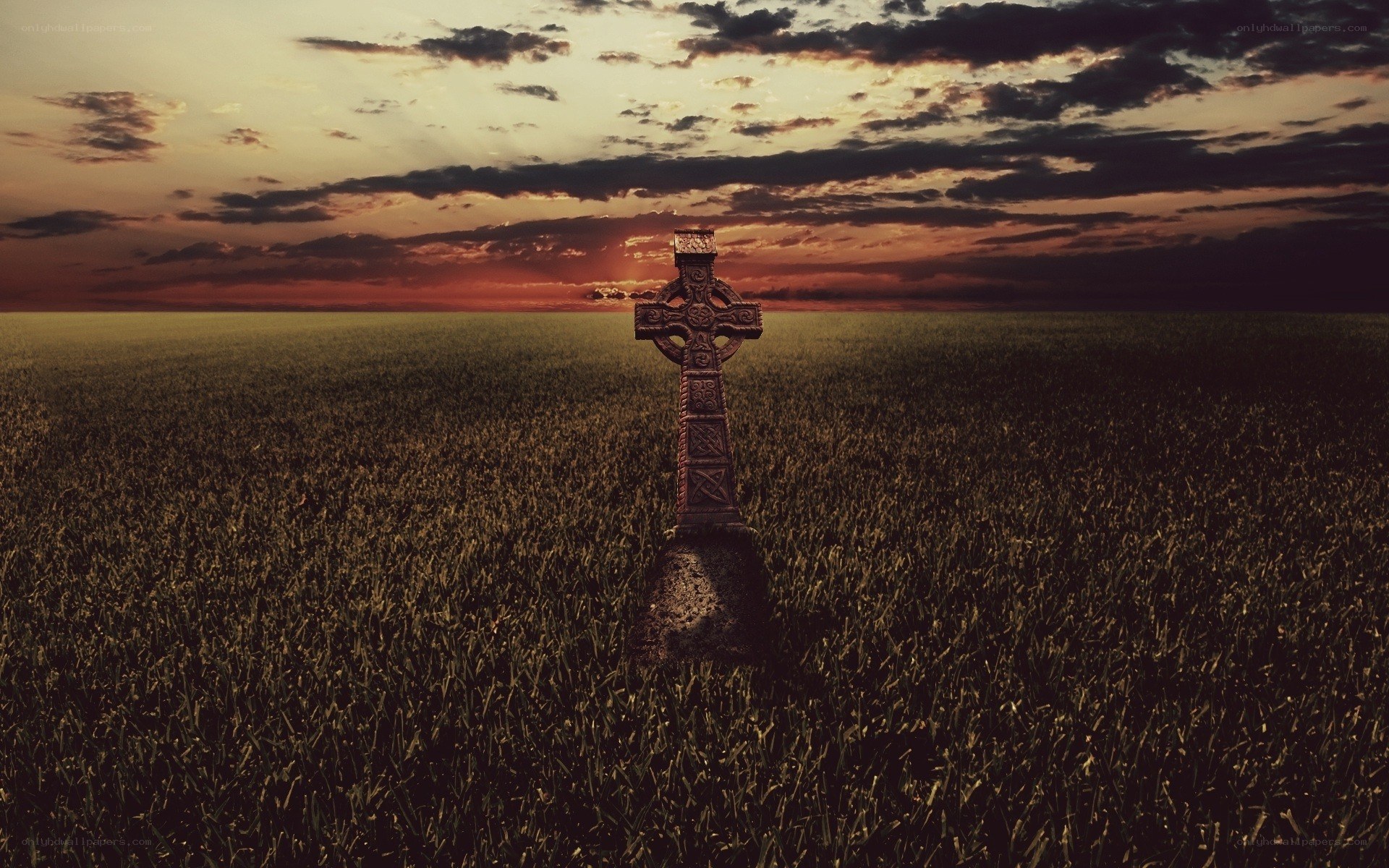 Celtic cross in a field at sunset