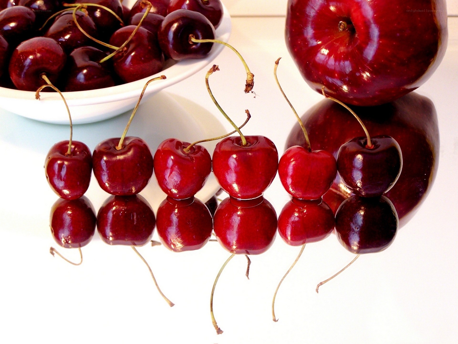 Cherries and apple on reflective surface