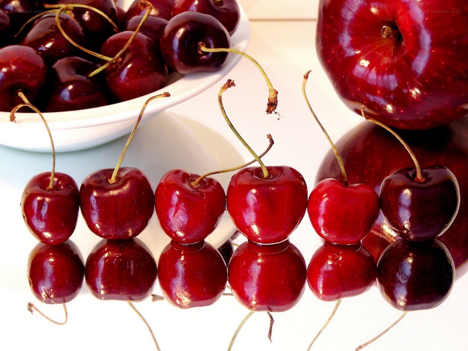 Cherries and apples on a reflective surface