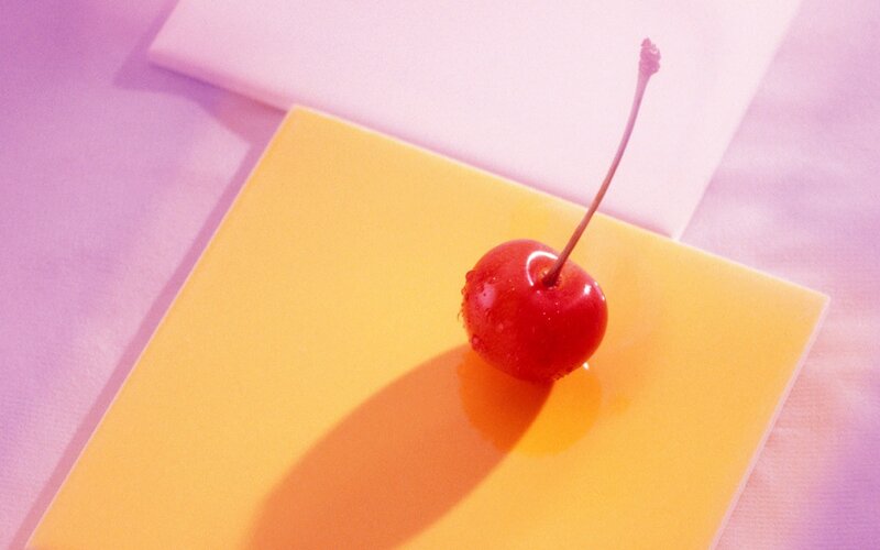 Cherry on a yellow surface