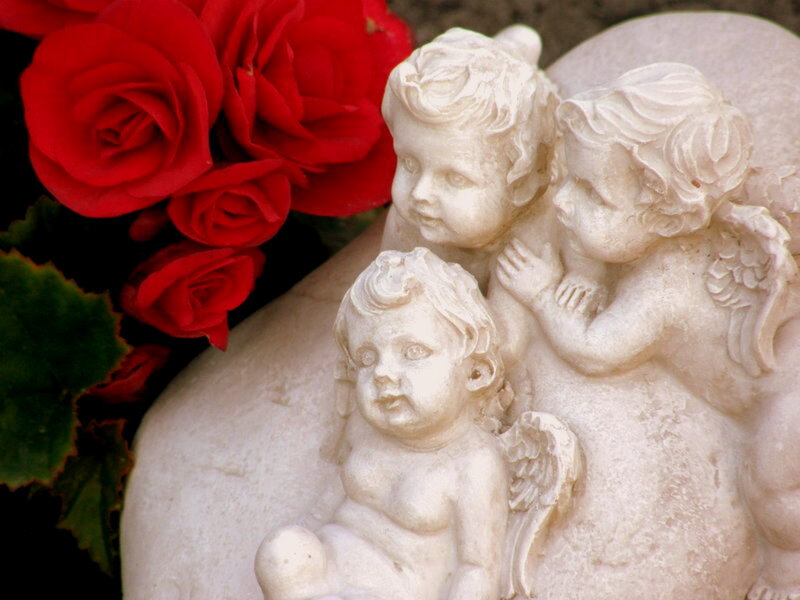 Cherub statue with red roses