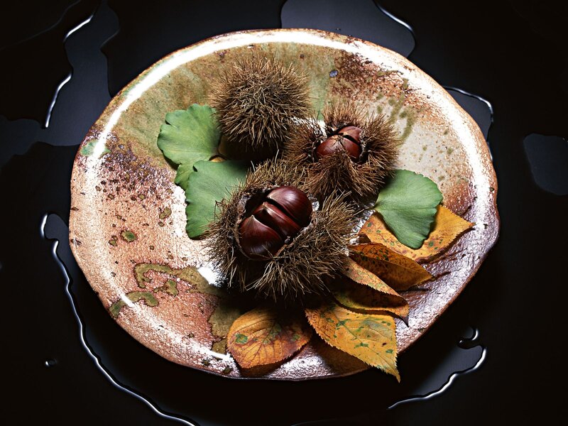 Chestnuts and autumn leaves on a plate