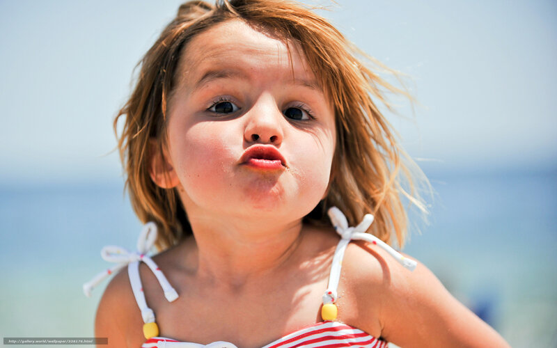child blowing a kiss at beach