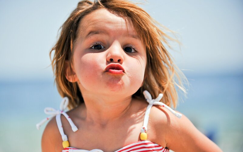 child blowing a kiss at the beach