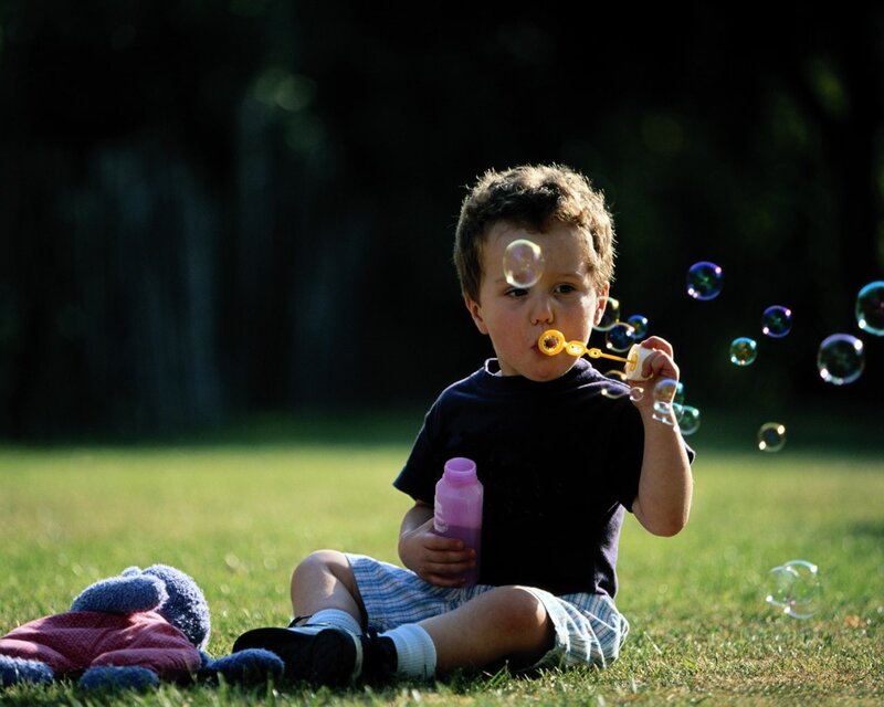 Child blowing bubbles in park