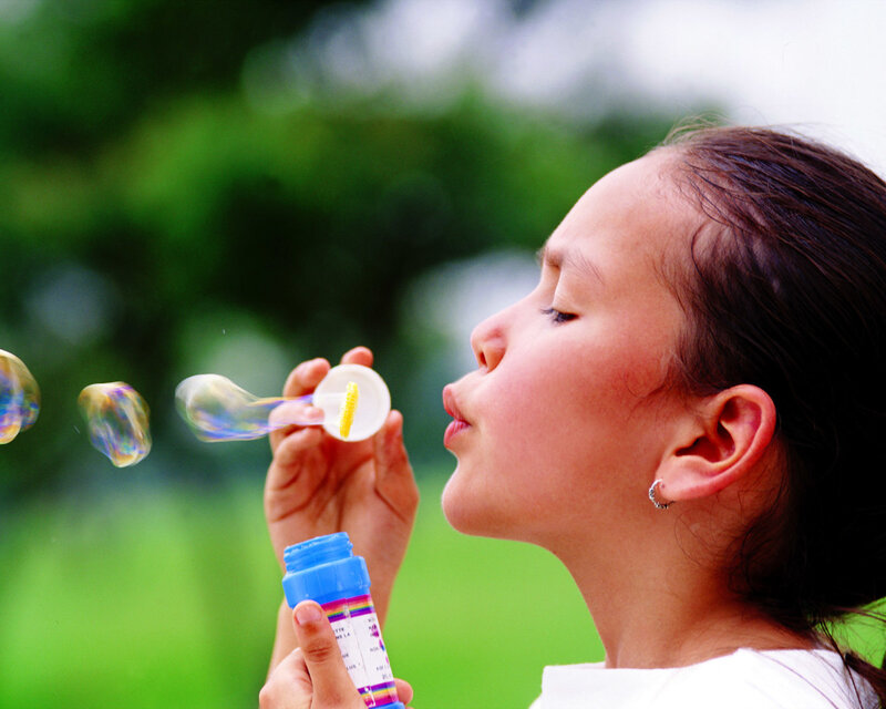 child blowing bubbles outdoors