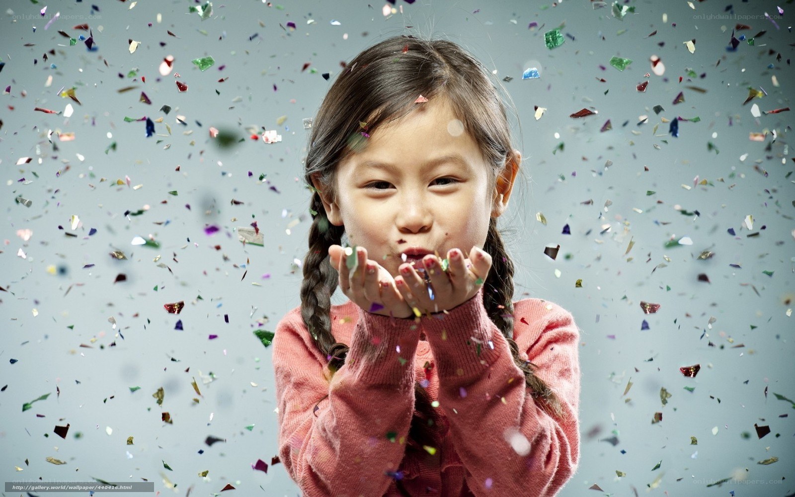 child blowing confetti