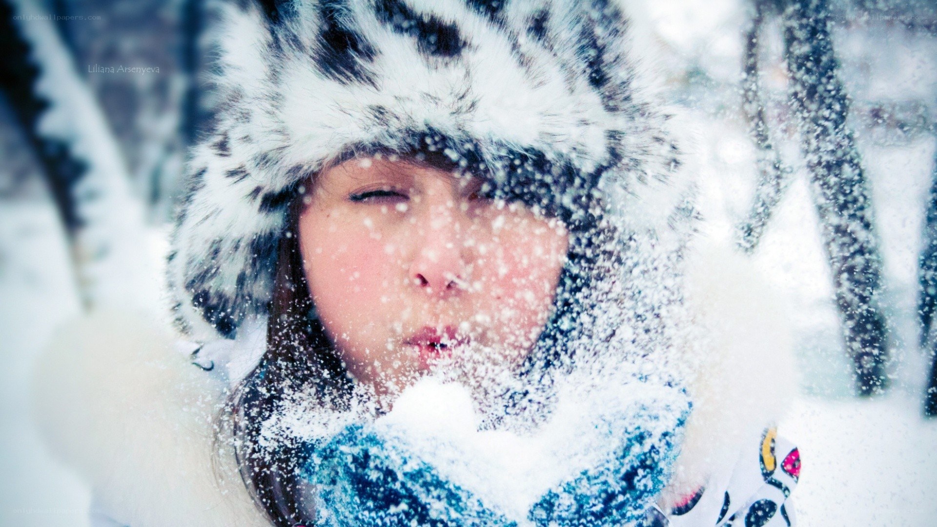 child blowing snow in winter