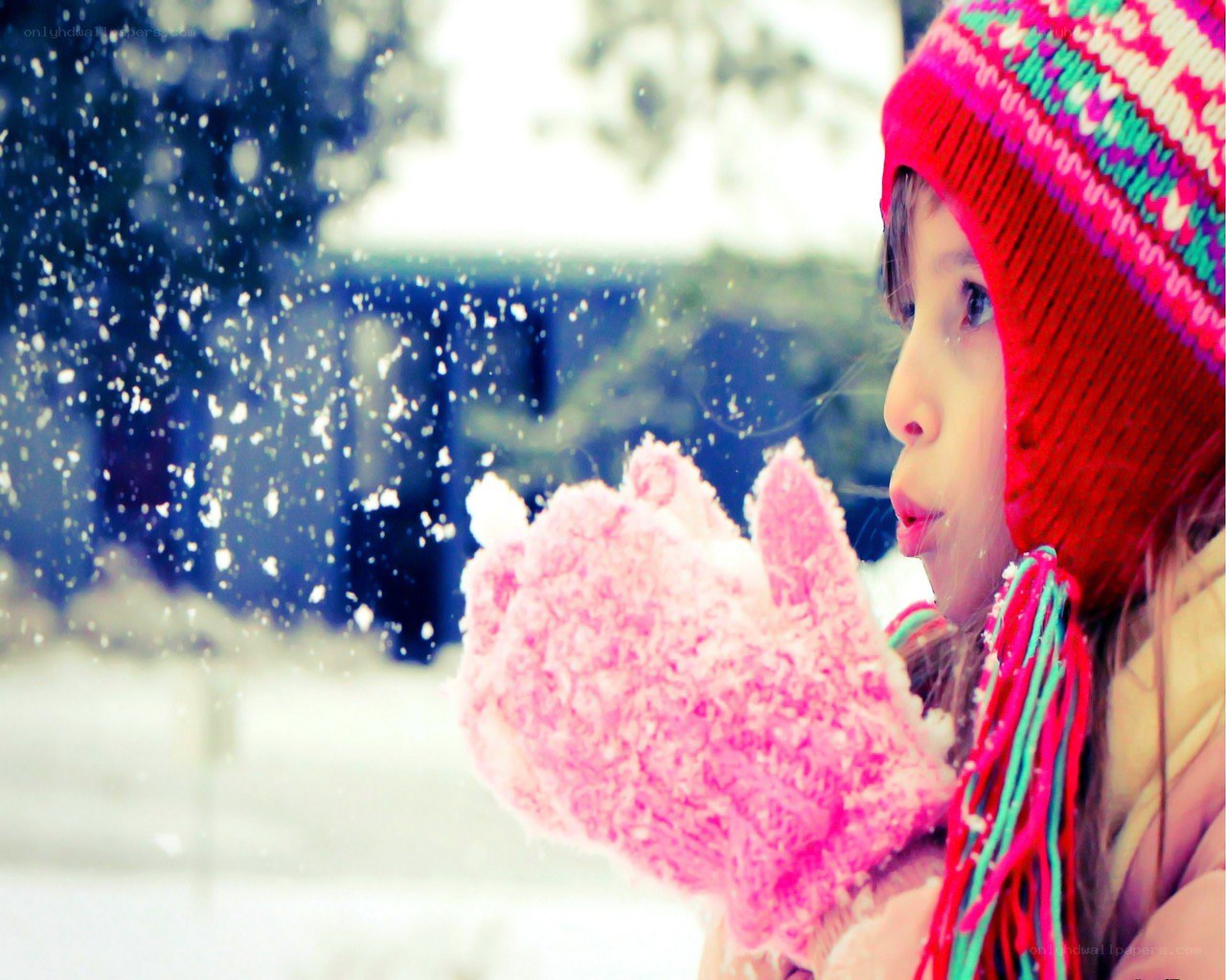 child blowing snow in winter