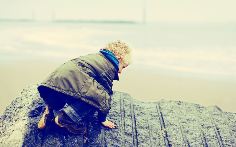 child climbing on a rock