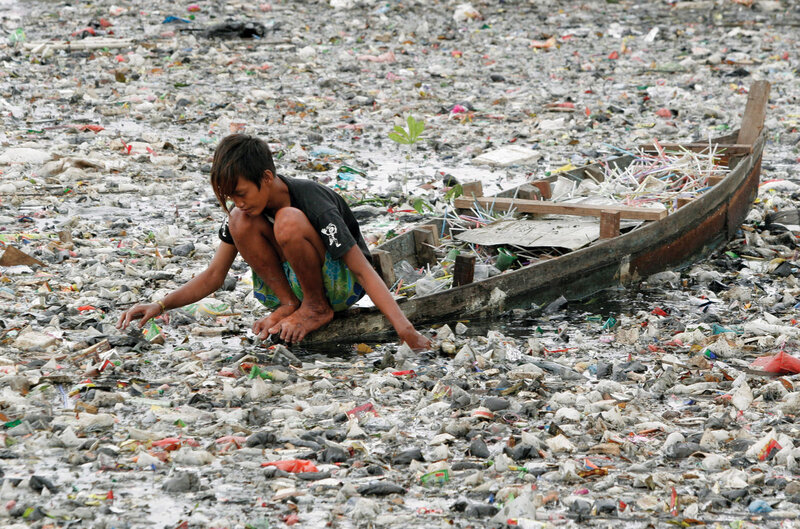 Child collecting trash in polluted water