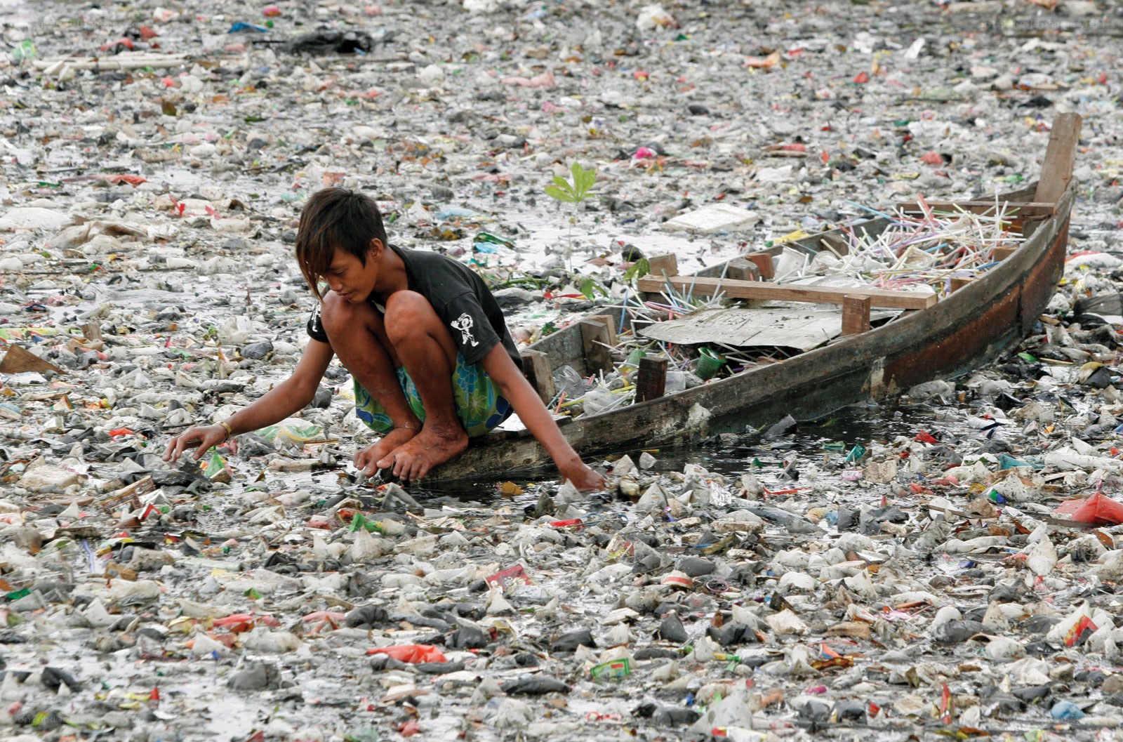 Child collecting trash in polluted water