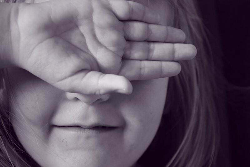 child covering eyes with hand