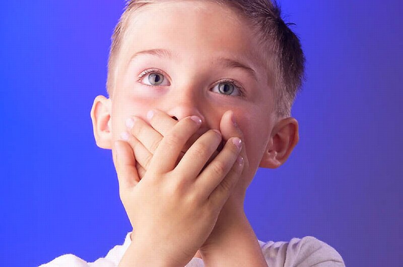 child covering mouth in surprise