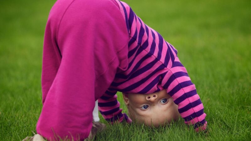child doing a handstand on grass
