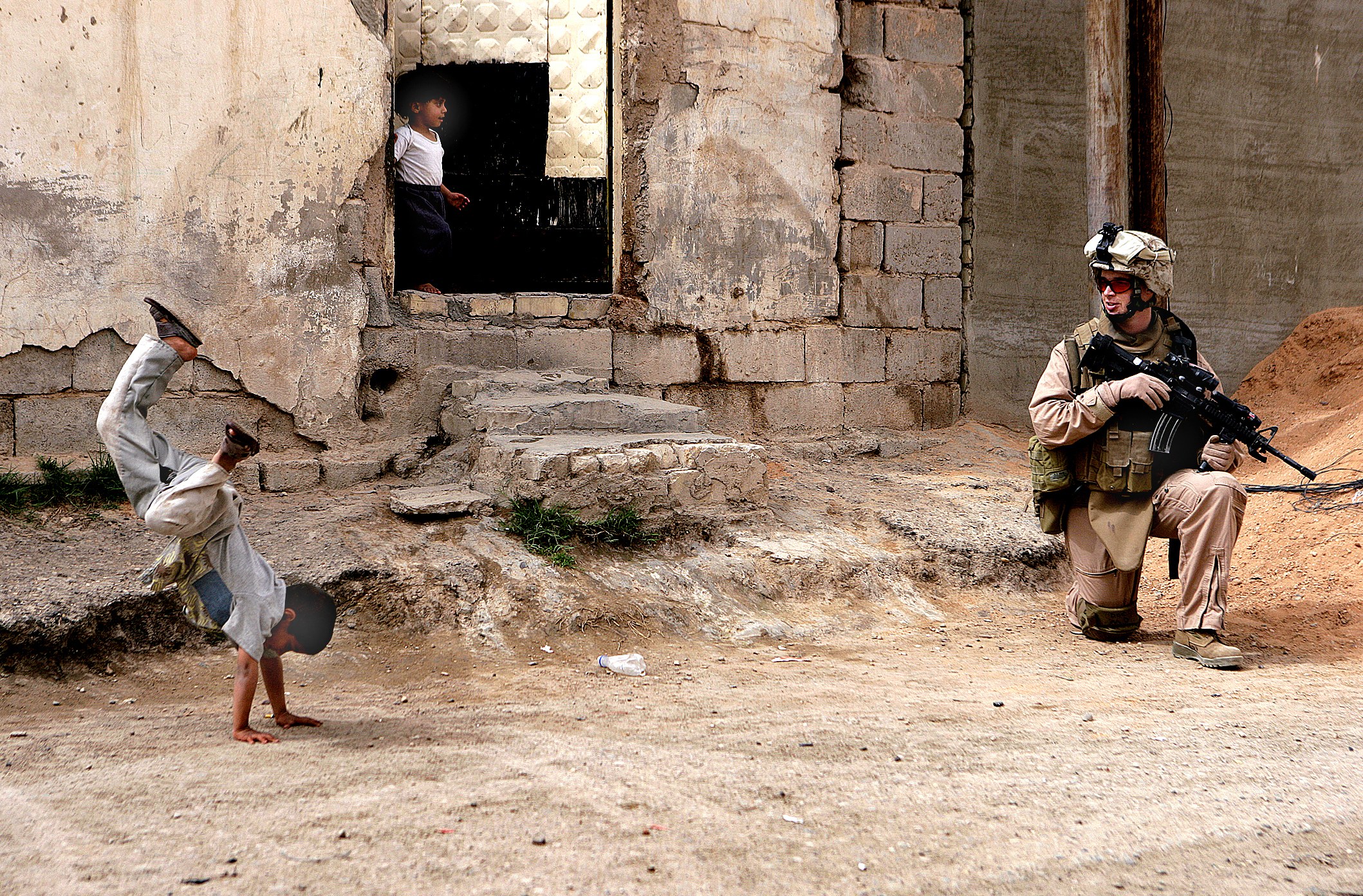 Child doing handstand near soldier