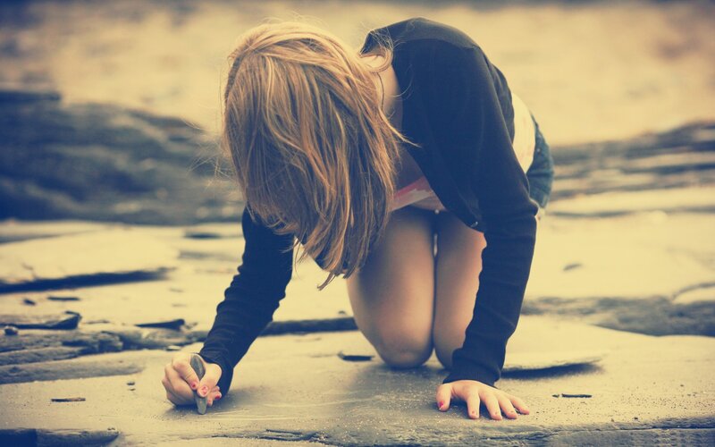 child drawing on beach