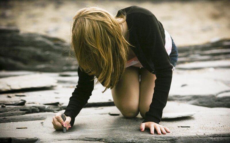 child drawing on stone