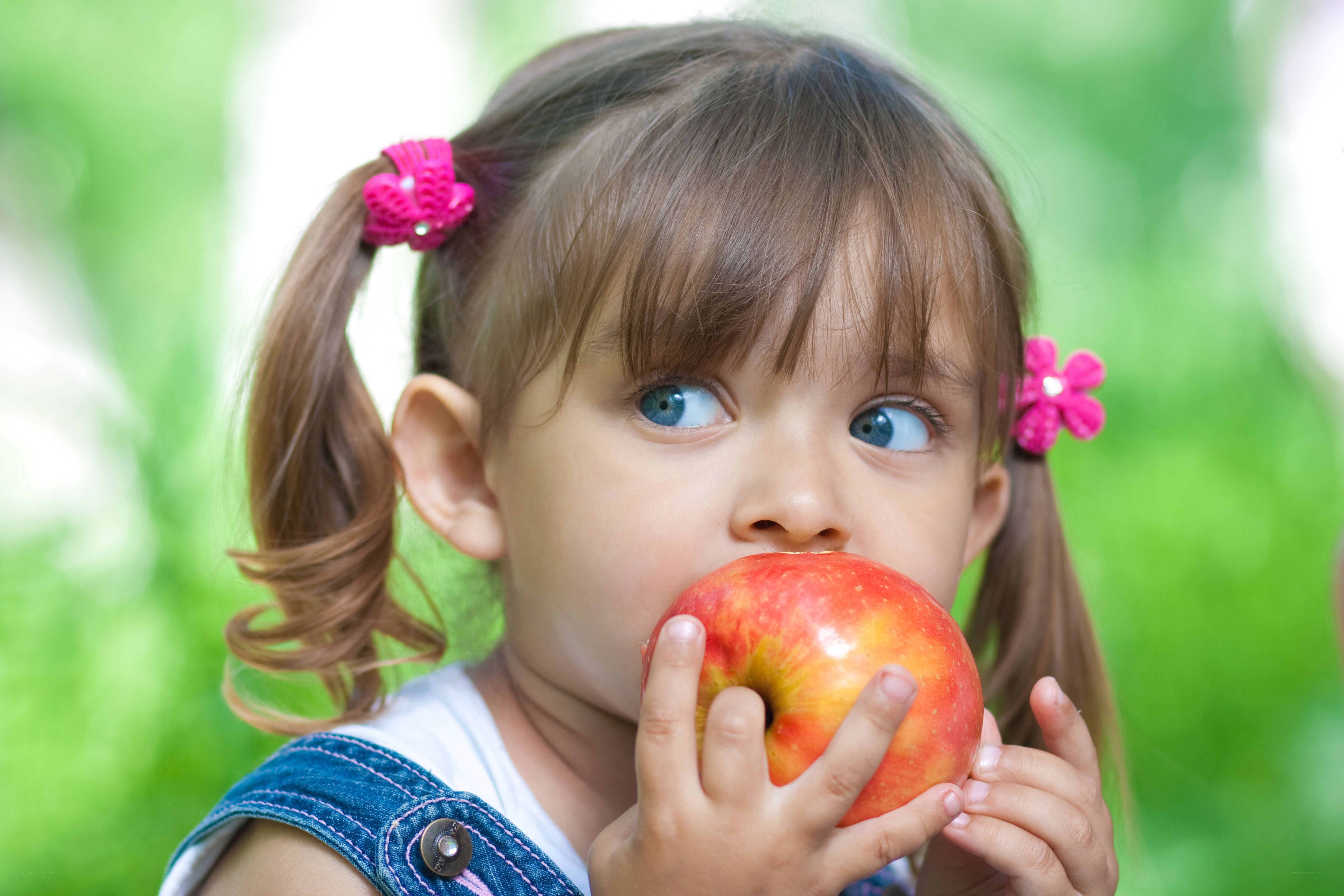 child eating red apple