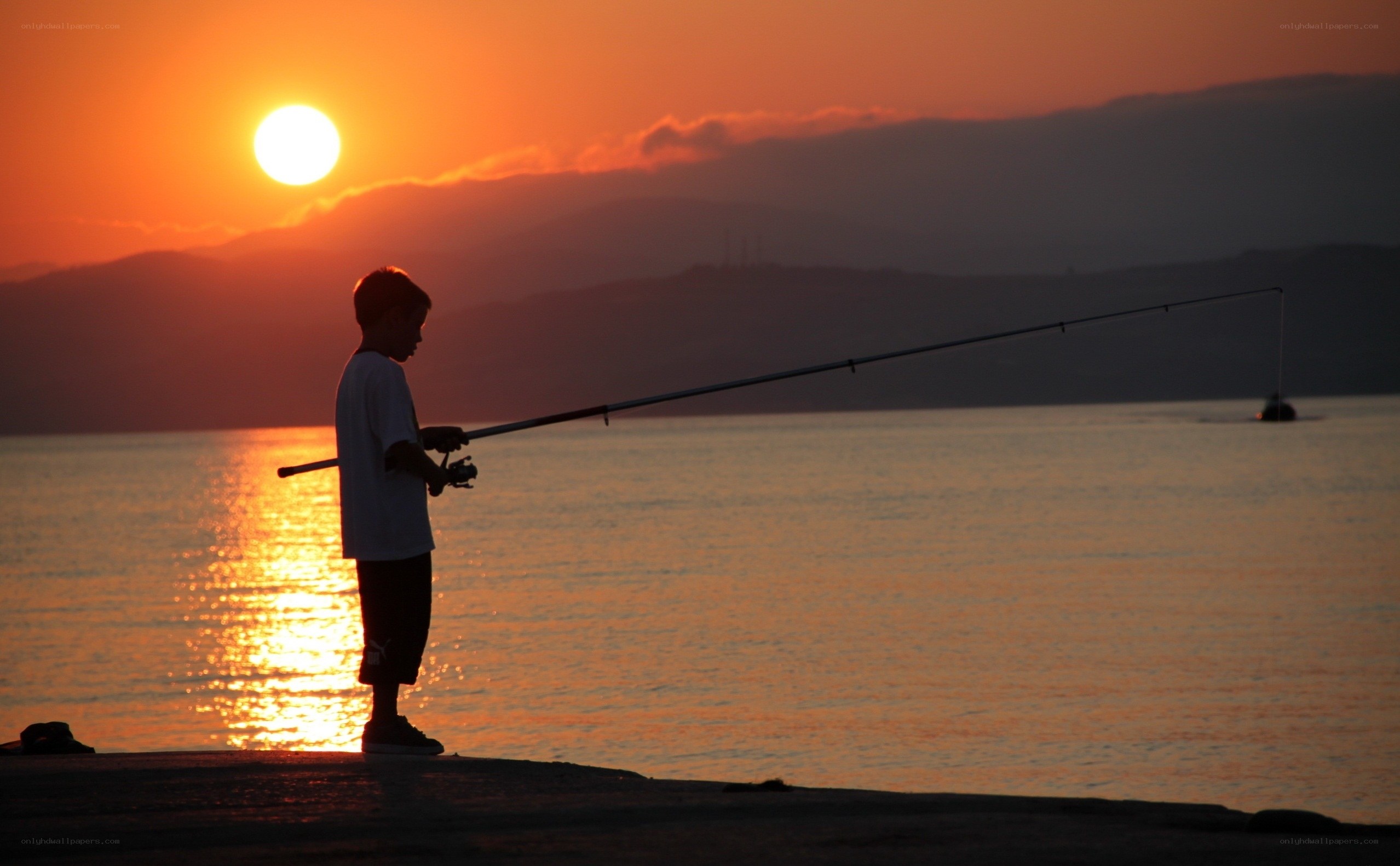 child fishing at sunset