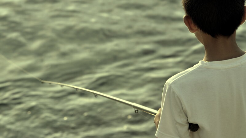 child fishing by the water