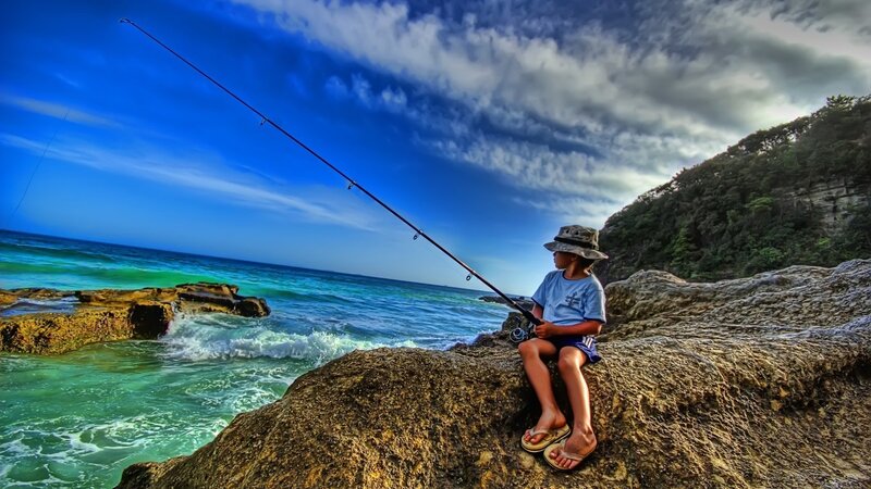 child fishing on rocky shore