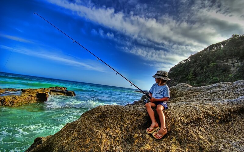 Child fishing on rocky shore