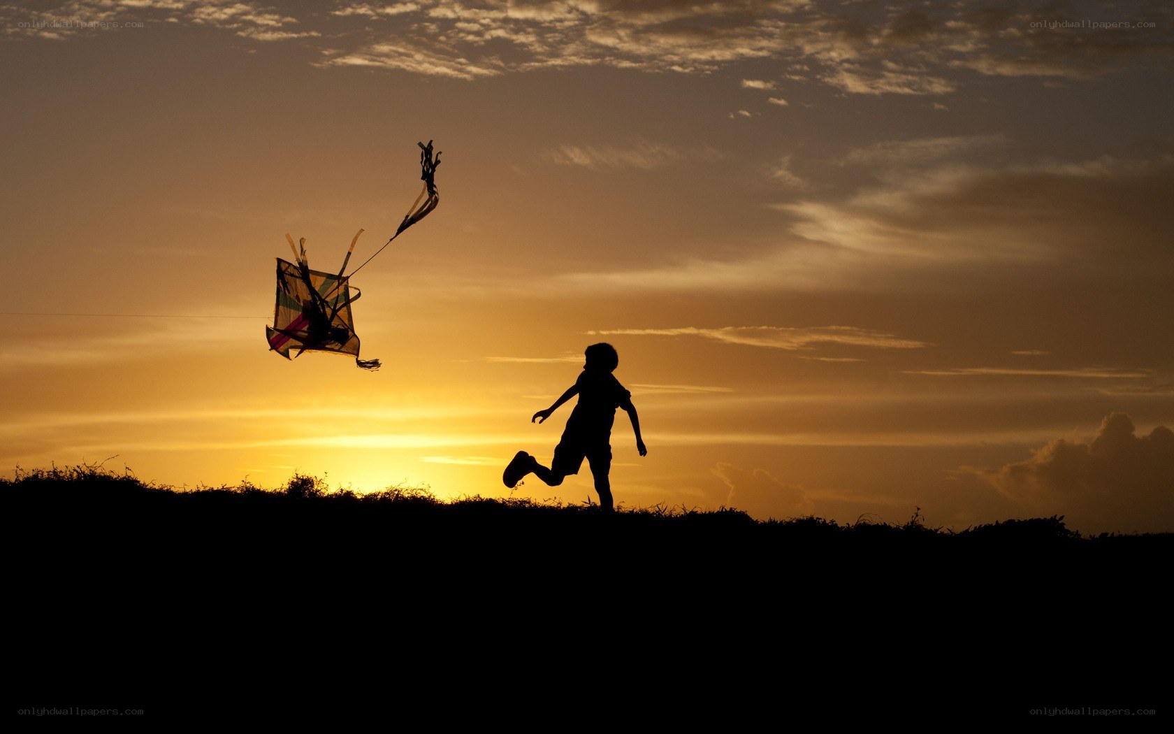 Child flying kite at sunset