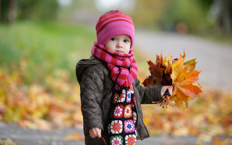 child holding autumn leaves