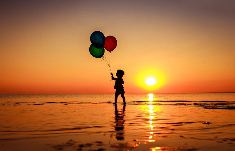 Child Holding Balloons — Orange