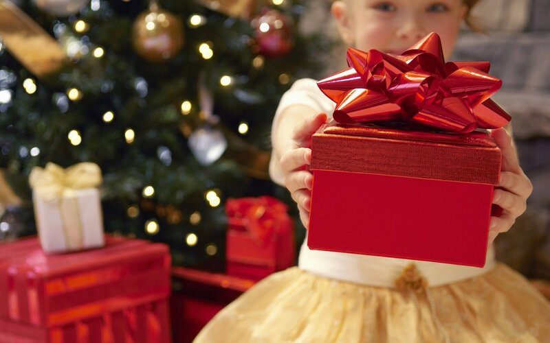 child holding gift near christmas tree