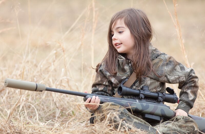 child holding rifle in field