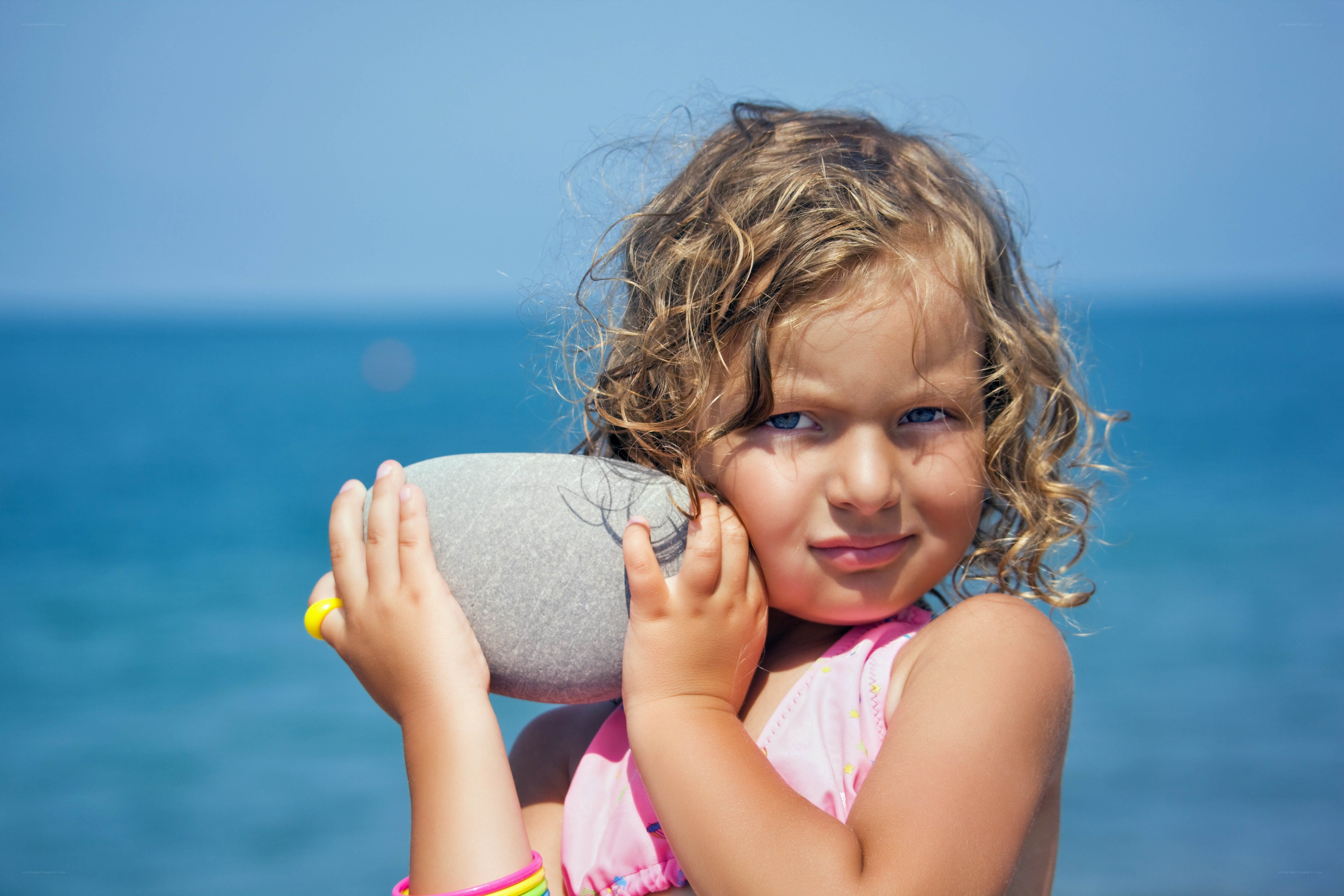 child holding rock at beach