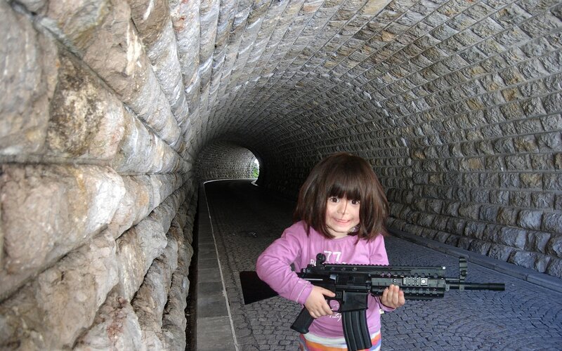 Child holding toy gun in tunnel