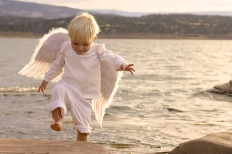 child in angel costume by water