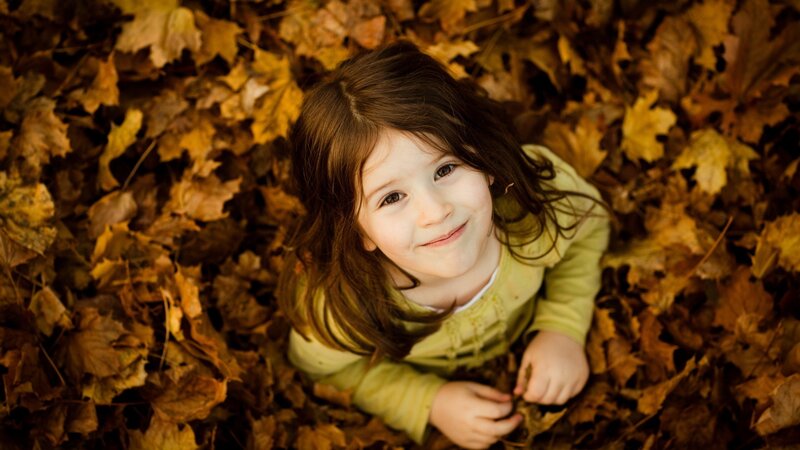 child in autumn leaves