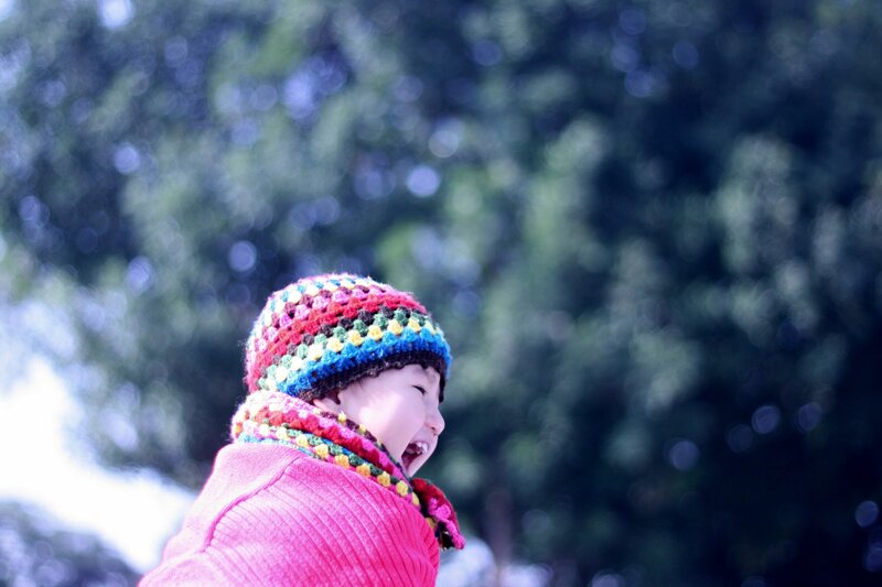 child in colorful hat laughing