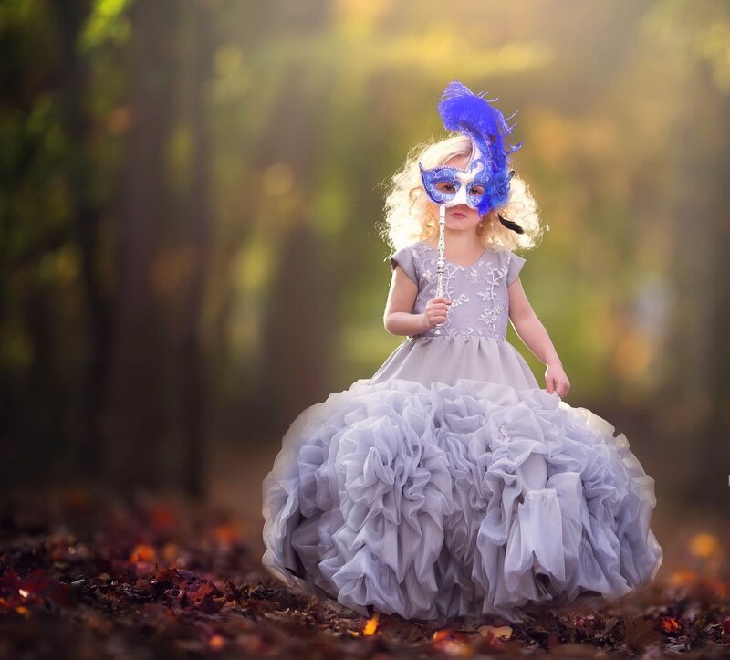 Child in Dress Holding Mask