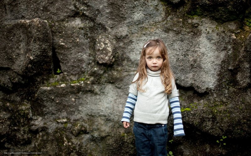 child in front of rock wall