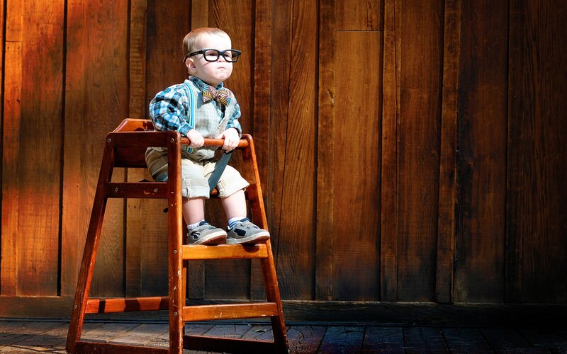 child in glasses on high chair