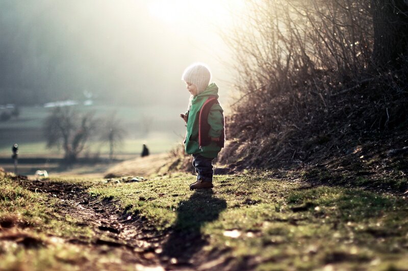 child in green coat at sunset