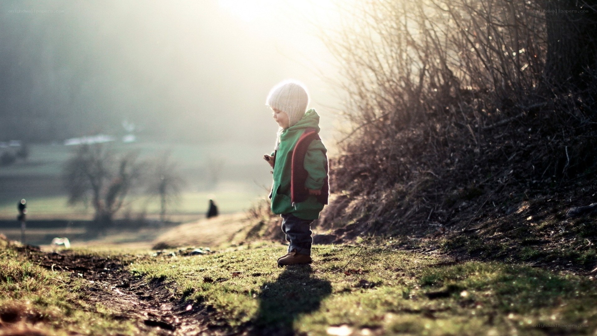 child in green coat at sunset