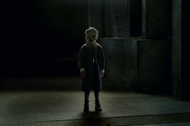 child in mask stands in dark room