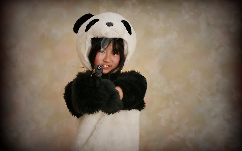 child in panda costume with toy gun