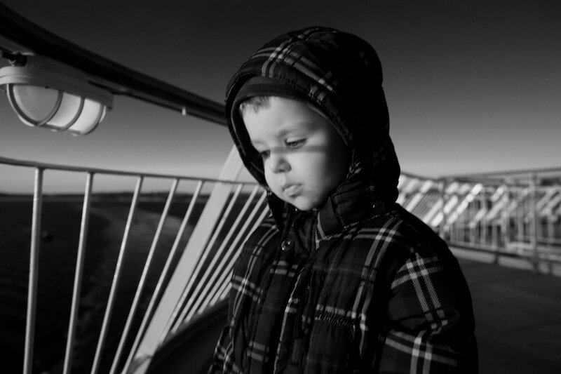 child in plaid jacket on bridge