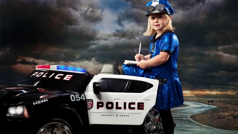 child in police costume with toy car