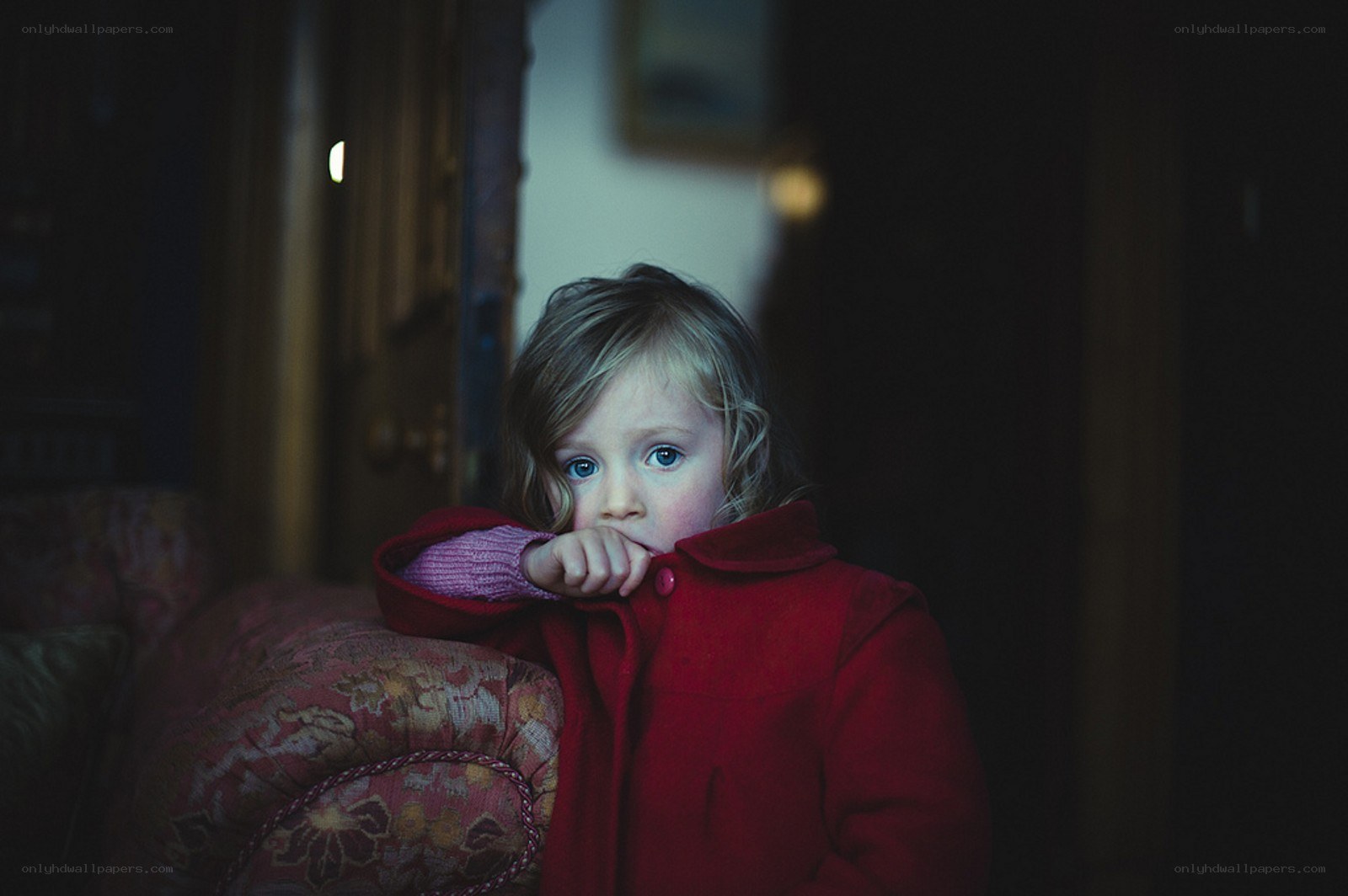 child in red coat looking at camera