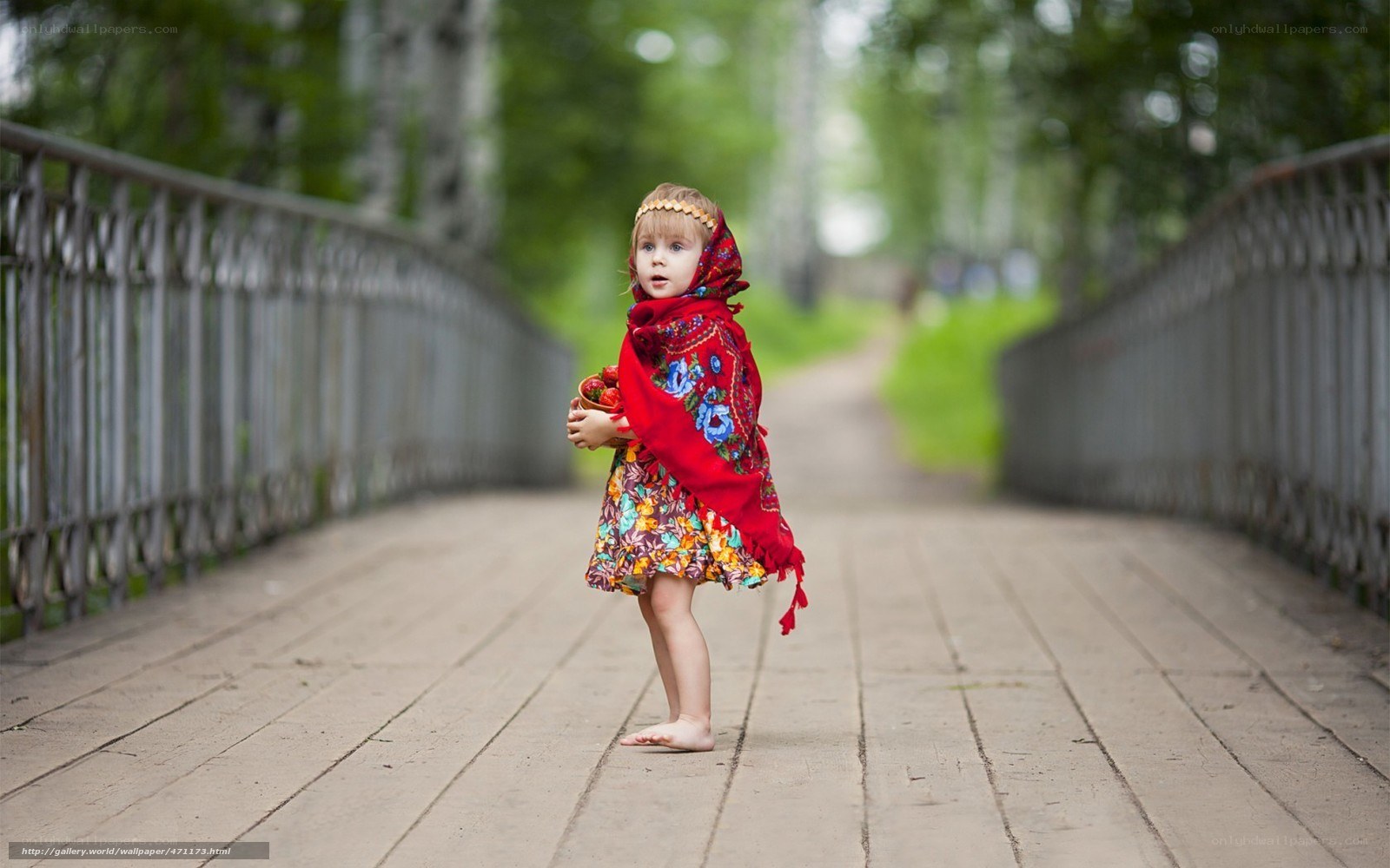 child in red shawl on bridge